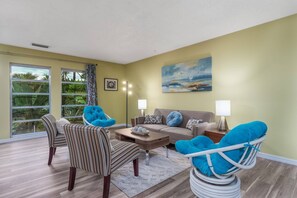 A lovely social area (living room) with comfortable seating and views of both the front yard and the swimming pool