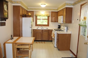 Kitchen with plates, coffee mugs, coffee maker, toaster, ice trays & glassware.