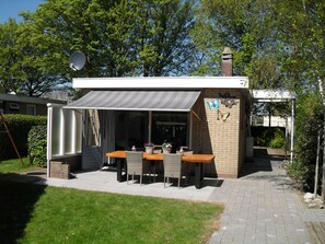 Voorkant van de woning , met het terras op het zuiden met  zonwering en parasol 