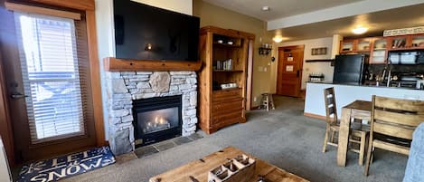 Living room with large TV, gas burning fireplace, and private deck.