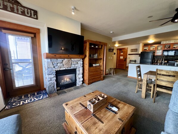 Living room with large TV, gas burning fireplace, and private deck.