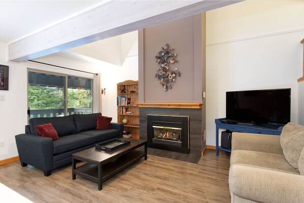 Cozy living room with gas fireplace and sliding door access to deck