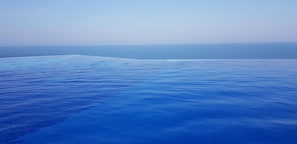 vista frontal da piscina borda infinita que mistura o seu azul com azul do mar