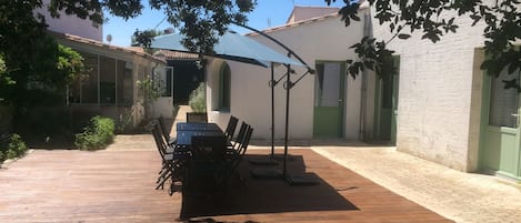 Tables et parasols vus du fond du jardin sous les arbres