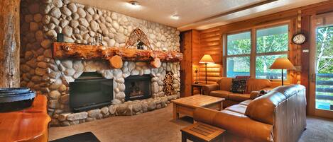 River rock fireplace with feature single log mantle, flat screen TV, full couch and love seat
