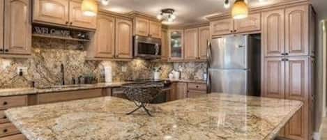 The fully stocked kitchen include granite countertops and custom cabinetry.