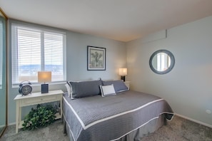 Bedroom with king size bed, TV, ensuite bathroom, vanity sink, dresser, lamp, and mirrored closet