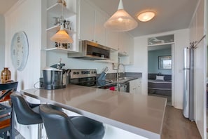 Kitchen with stainless steel appliances, sink, overhead lighting, blender, sink, dishwasher, coffee maker, toaster, recessed lighting and entrance to bedroom