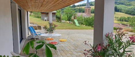 Terrasse couverte du gite avec 2 bains de soleil et une table et 4 chaises