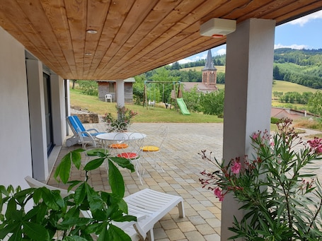 Terrasse couverte du gite avec 2 bains de soleil et une table et 4 chaises