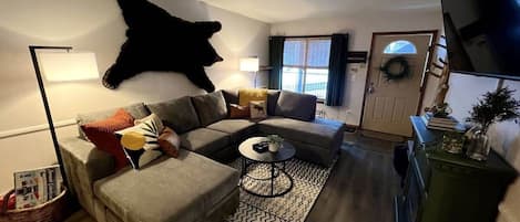 This Gold Creek condo is located in the heart of Breckenridge and features a cozy family room with a large sectional sofa, a flat-screen TV, and an electric fireplace.