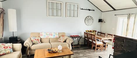 View of the living room (with a wood burning fireplace) and dining area.