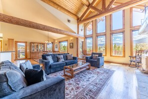 Main level living area with gas fireplace, hardwood flooring, vaulted ceilings, floor to ceiling windows and ample seating.