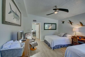 The bedroom has 2 queen beds, TV, wood tile flooring, remote ceiling fan and a leather chair to relax upon.