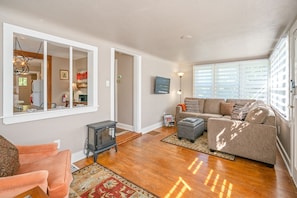 Bright entry way and living area, with ROKU TV, electric fireplace and couch.