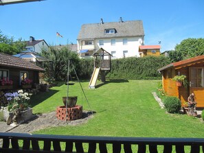 Garten mit Grillplatz und Baumhaus mit Rutsche.