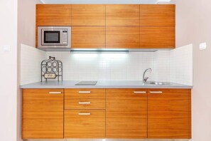 Kitchenette with an induction hob, refrigerator with freezer and microwave.