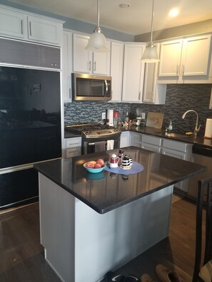 Kitchen with sub-zero fridge, gas stove, and large kitchen island.