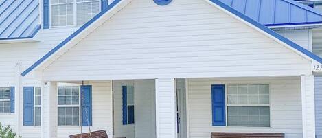 Front of house with porch swing and bench 