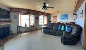 Large main floor family room with table, TV, fireplace, lake views