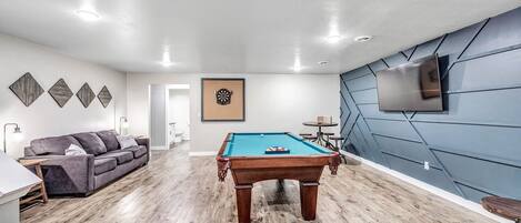 3 piece slate pool table, pull out  queen sofa sleeper, 65" Smart TV, dart board, and pub seating for 8.