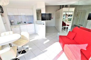living room with sofa, dining table and open equipped kitchen