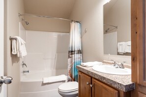 Bathroom with view of mirror and shower decorated with a shower curtain that includes a picture of the grand prismatic located in Yellowstone National Park.