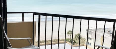 Small balcony off Master bedroom with two high back chairs and an ocean view