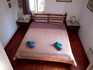 Double en suite bedroom featuring a powerful ceiling fan, large storage for clothing, one wall fitted electric panel for heating, one window facing the garden, and bookshelves.  