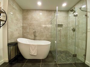 1 spacious bathroom with step-less walk-in river rock floor frameless shower and soaking tub with shower wand.