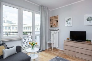 Living room with a sofa bed, TV and access to the balcony.