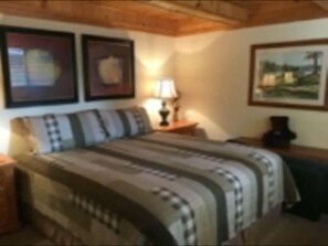 The master bedroom with California King bed, looks onto the back deck and forest