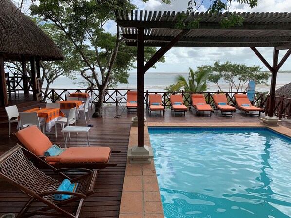 Pool deck overlooking the ocean, with loungers and support staff