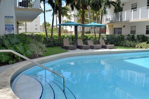 Large swimming pool with poolside loungers and umbrellas