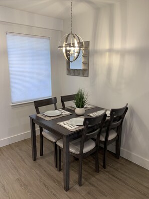 Dining area for 4, chandelier with dimmer, cellular shades on all windows. 