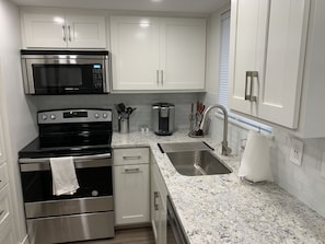 Modern Kitchen with white ice granite countertops, glass tile backsplash, soft close custom cabinets, pull out trash can, kitchen aid dishwasher, sharp convection microwave, keurig k-elite,  Amana smooth top range, and recessed led lighting.