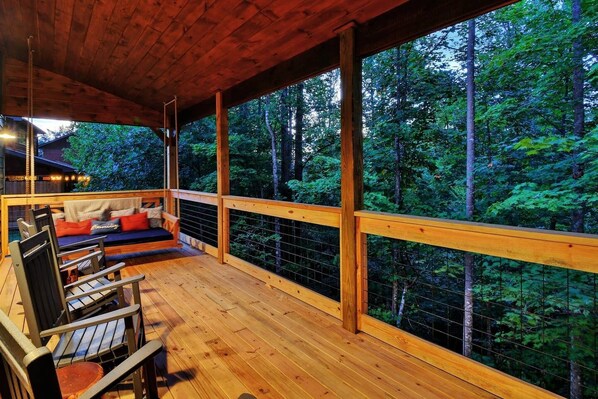 Experience the beauty of nature from the comfort of our outdoor deck, complete with a hanging bed swing and rocking chairs. Relax and soak up the breathtaking views of the forest and wildlife snuggle up with a good book in this tranquil oasis.