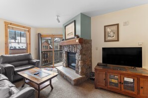 Living area with a queen sleeper sofa, fireplace, TV, and balcony access.