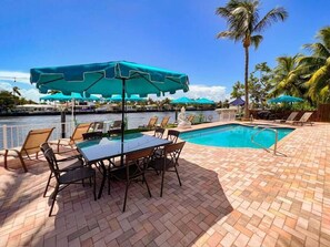 The back patio with big 8 seater tables, 2 BBQ's  umbrellas and sun loungers