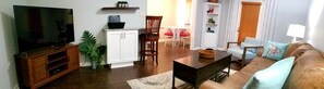 Living room has wrap around bar to kitchen with bar stools for extra seating. 
