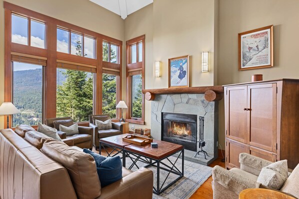 Open-concept living area with couches, a wood-burning fireplace, leather sofas, and TV
