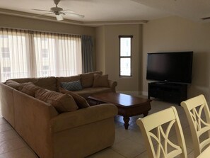 Living room with sectional, flat screen tv, and access to private balcony.