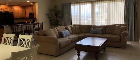 Living room with sectional, flat screen tv, and access to private balcony.