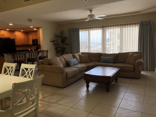 Living room with sectional, flat screen tv, and access to private balcony.