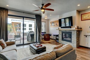 Sofa, Coffee Table, Ceiling Fan, TV, Fireplace, and Sliding Doors to the Balcony.