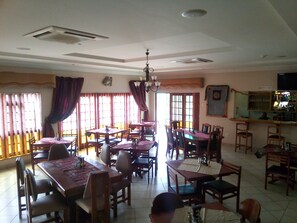 RESTAURANT MARIMBA. DRAPED DOUBLE SLIDING DOORS OPEN TO CAR PARK AND BALCONY.