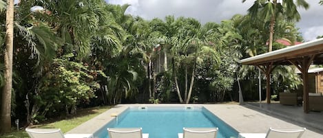 Grande piscine sécurisée avec un beau jardin tropical