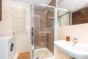 Bright bathroom with washing machine and shower cabin. 
