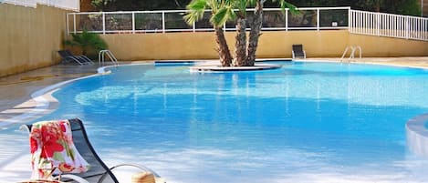 Lounge by the seasonal outdoor pool in the sunshine.