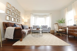 The front door opens into a light-soaked living area with high ceilings. 